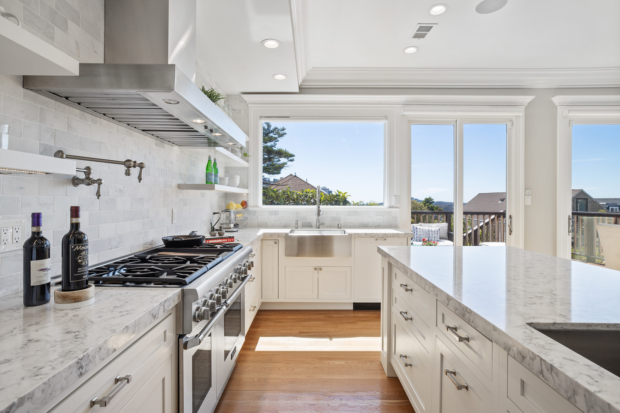 View of the kitchen, showing the high-end stainless steel stove, marble counters and sink