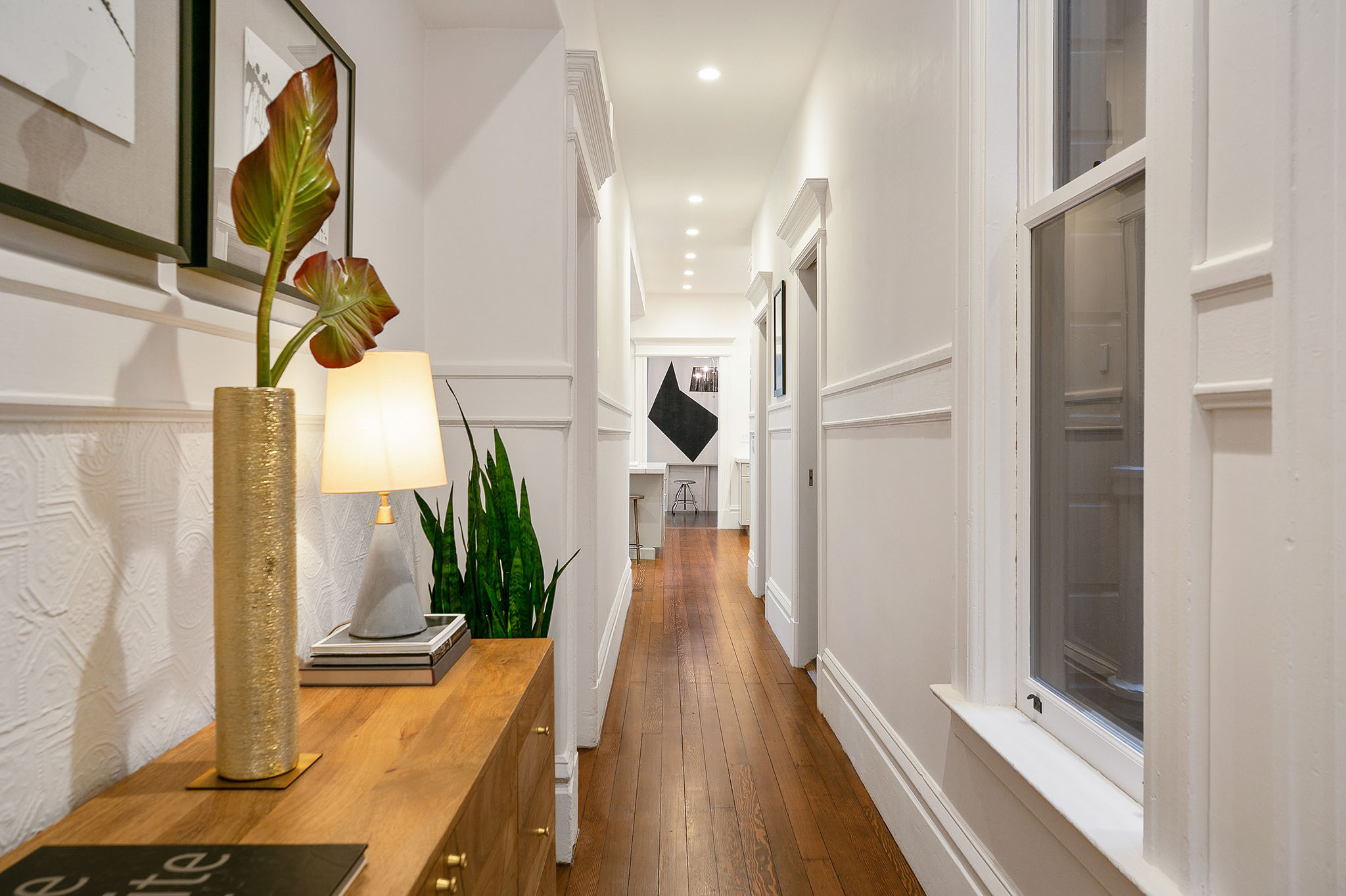 24 View of the hallway, featuring wood floors and white wainscoting