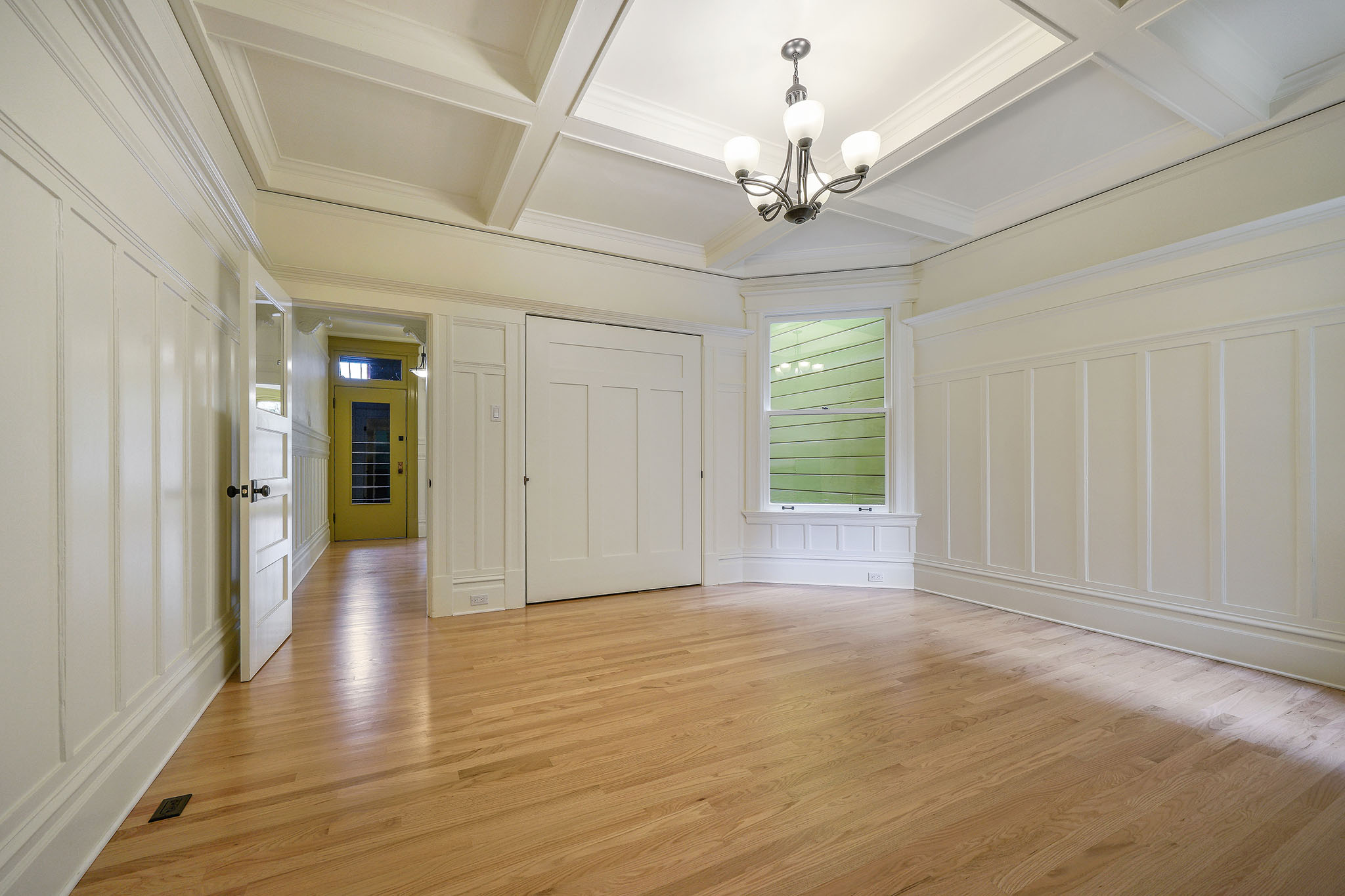 A large living room with white boxed wood ceilings and wainscoting