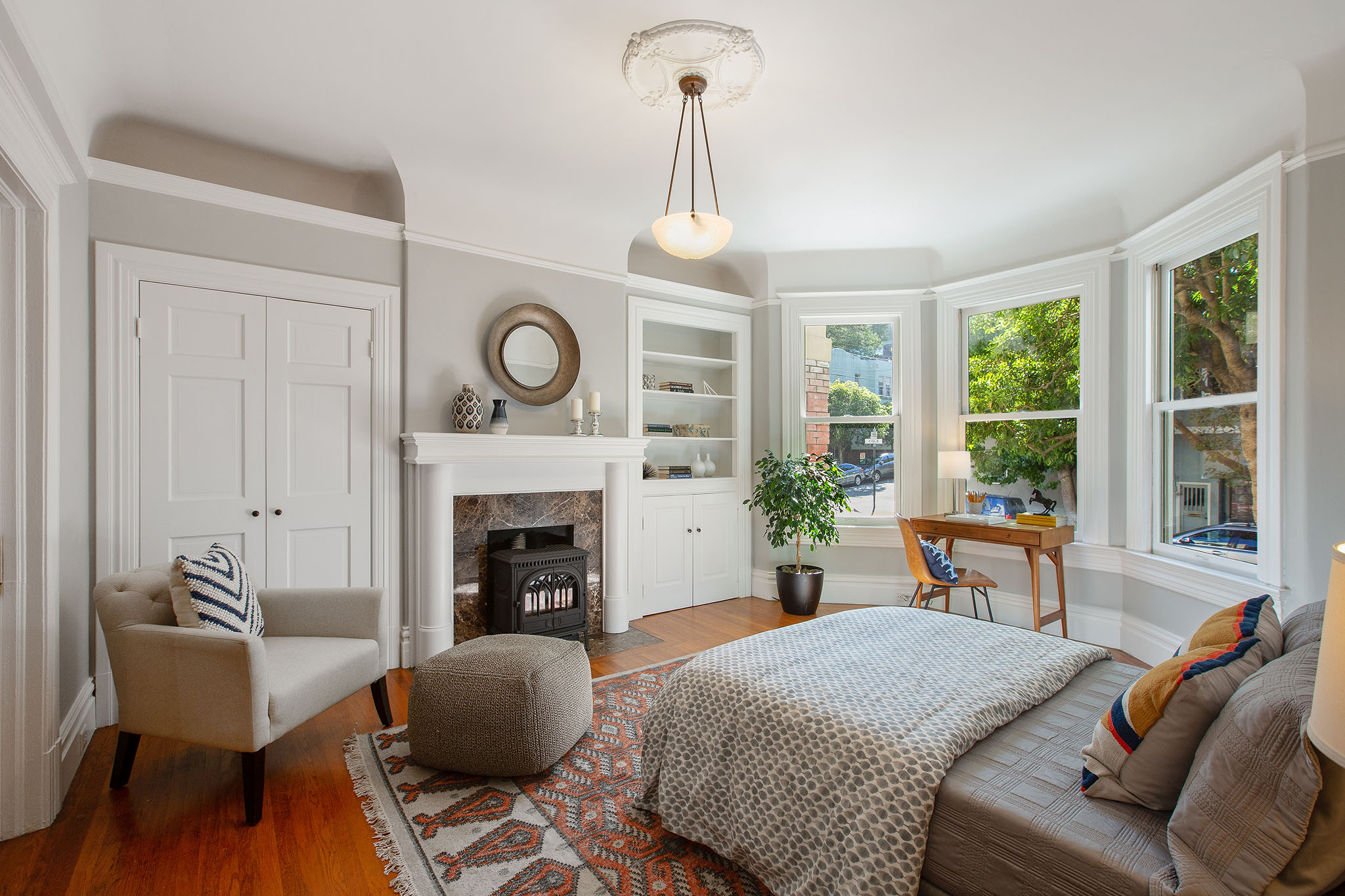 Bedroom with fireplace, wood floors and bay window