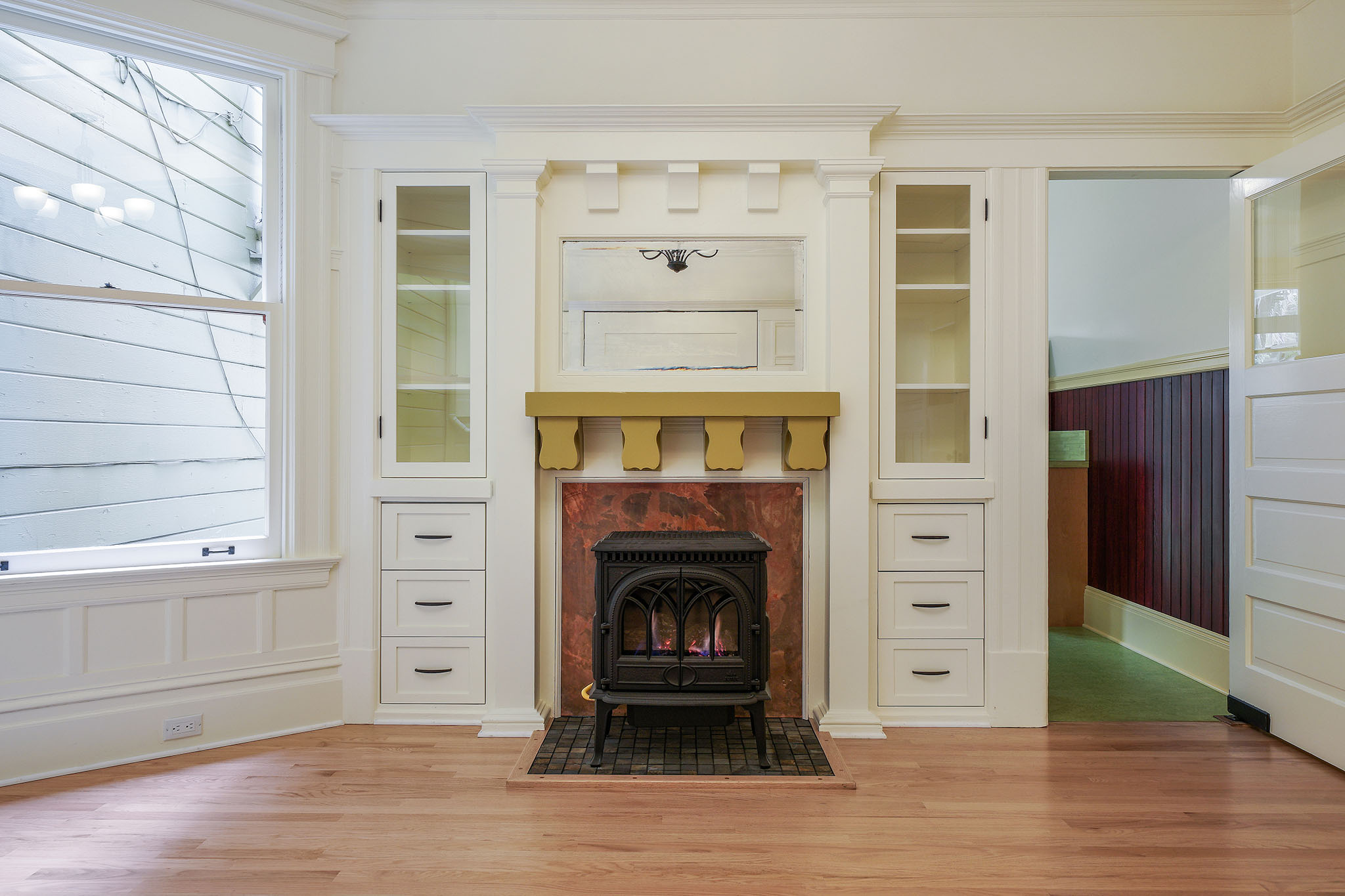 Close-up of the fireplace, and cabinets, showing a mirror above the mantle