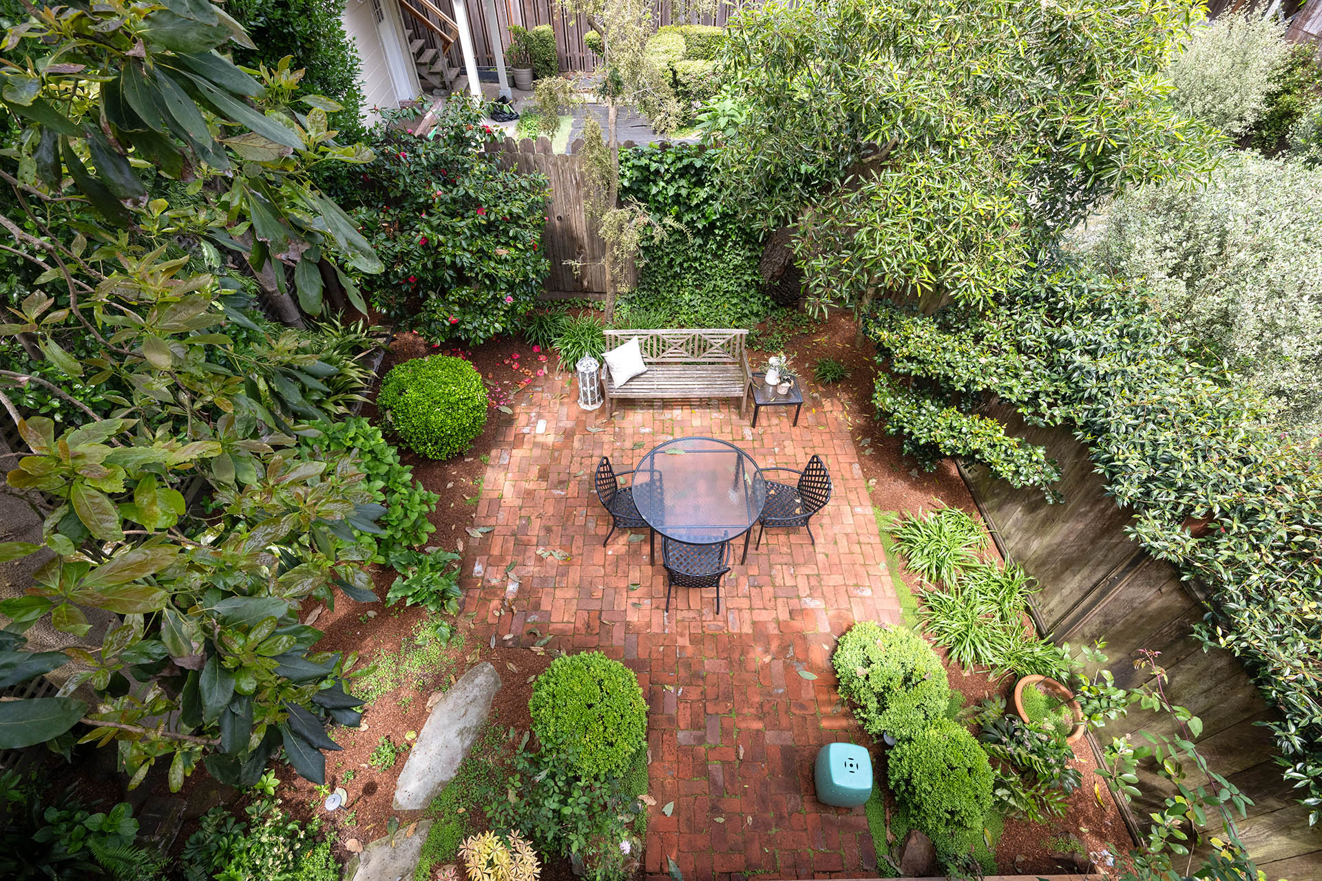 Shared yard has lots of lush greenery and brick patio.