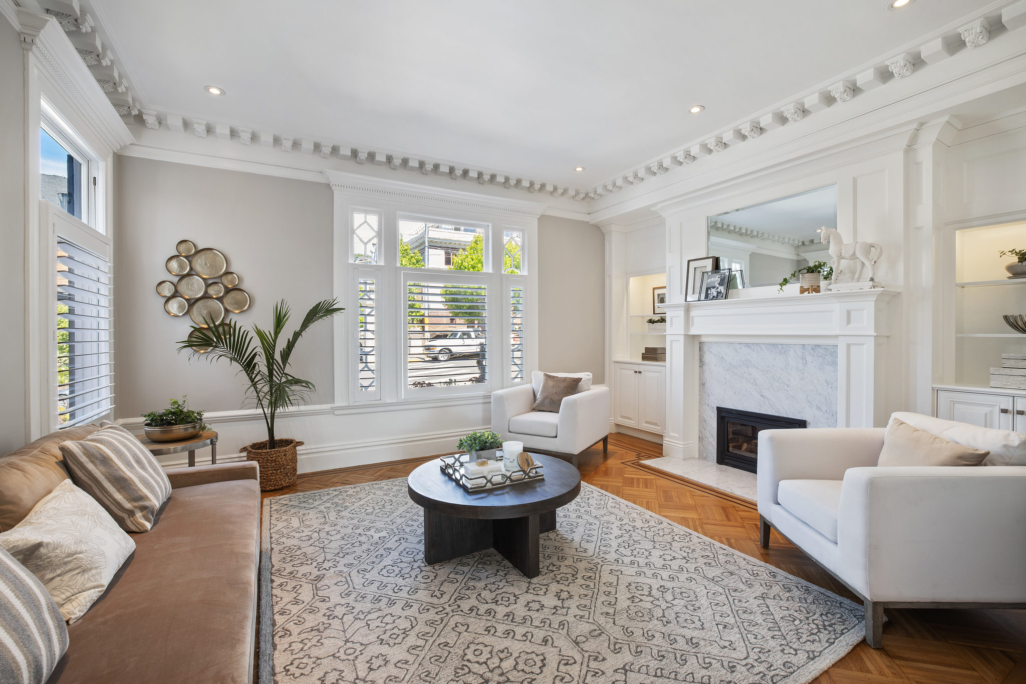 View of the formal living room, with wood floors, fireplace, and ornate crown moulding