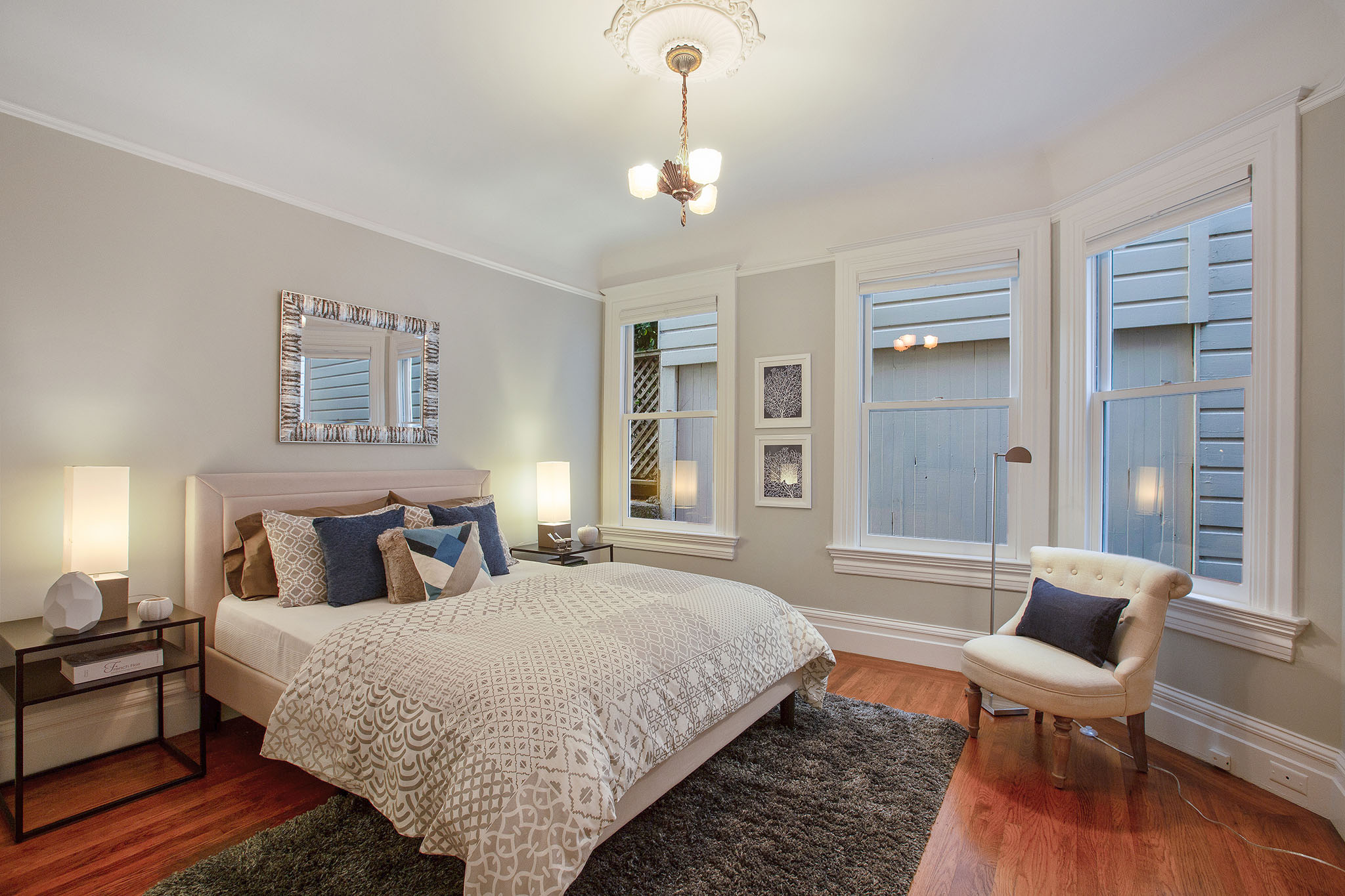 View of a second bedroom, featuring wood floors and three large windows