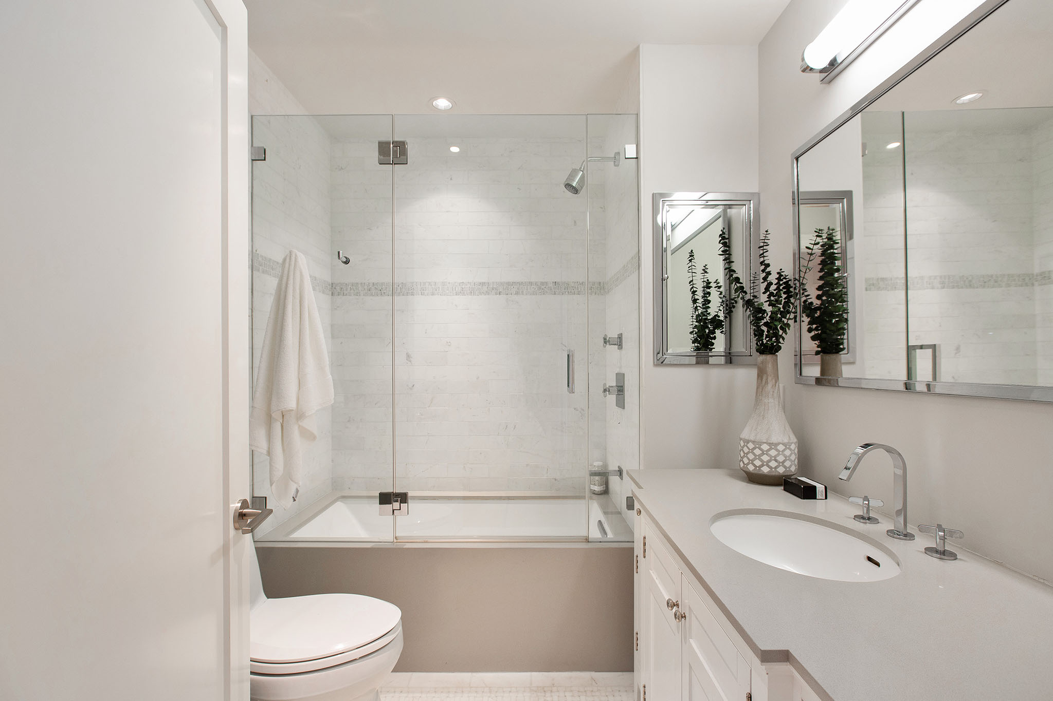 First bathroom has a tub/shower combo. There is one sink and grey countertops.