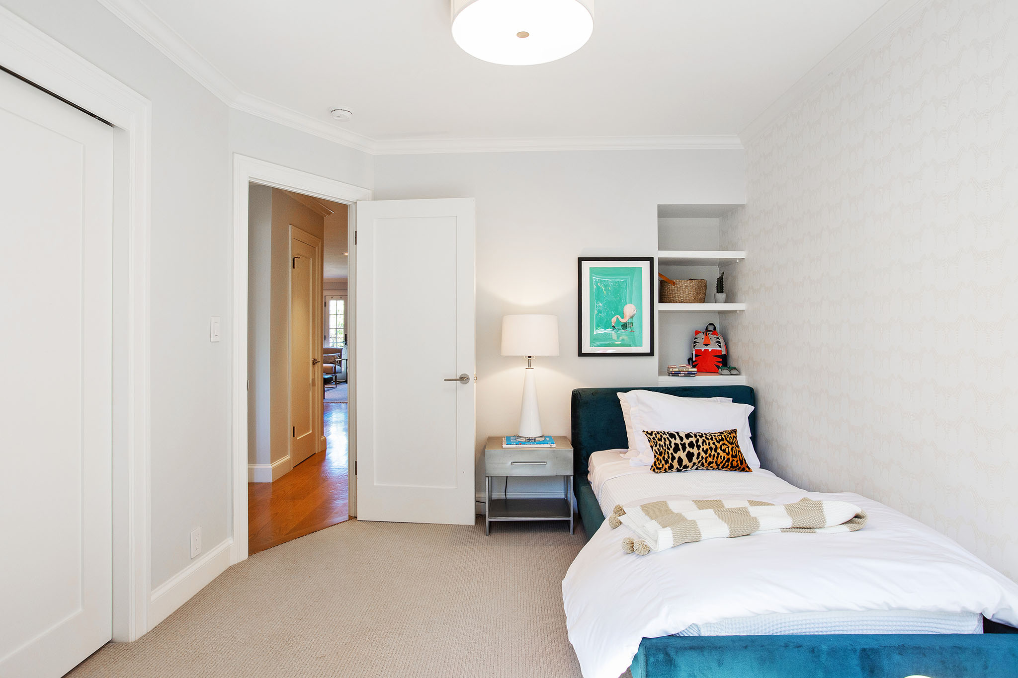 Second bedroom has light grey carpet and built in shelves above bed.