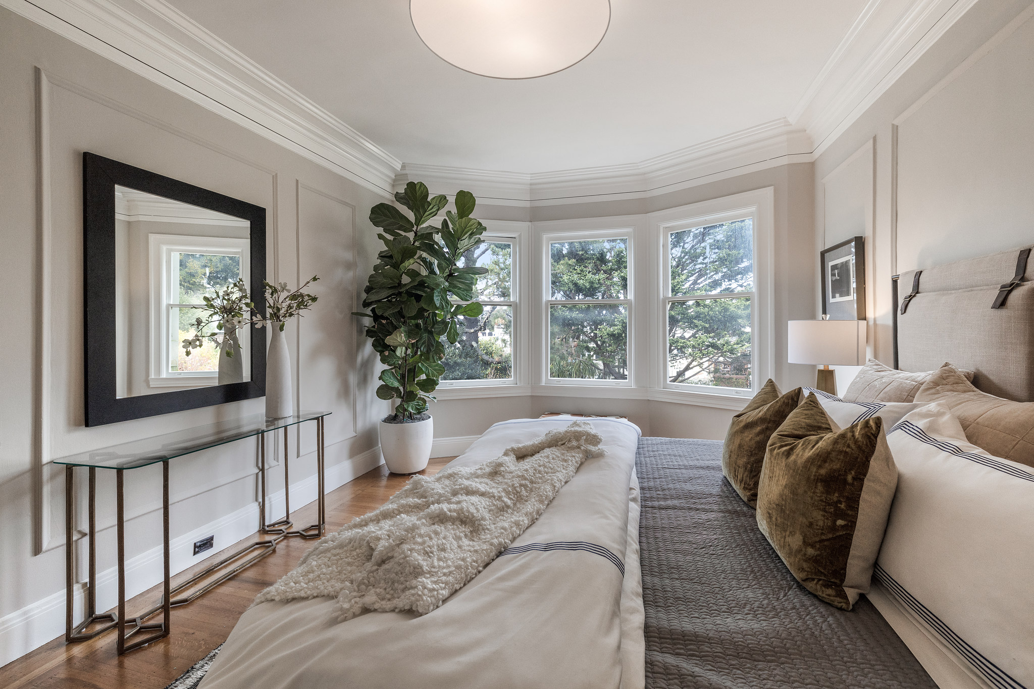 Primary bedroom, featuring three large windows and wood chair rail design