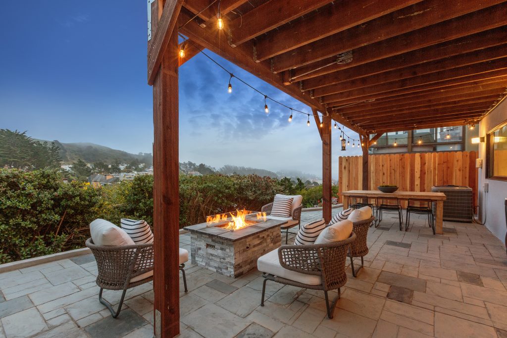 An outdoor fireplace and chairs with views of the city
