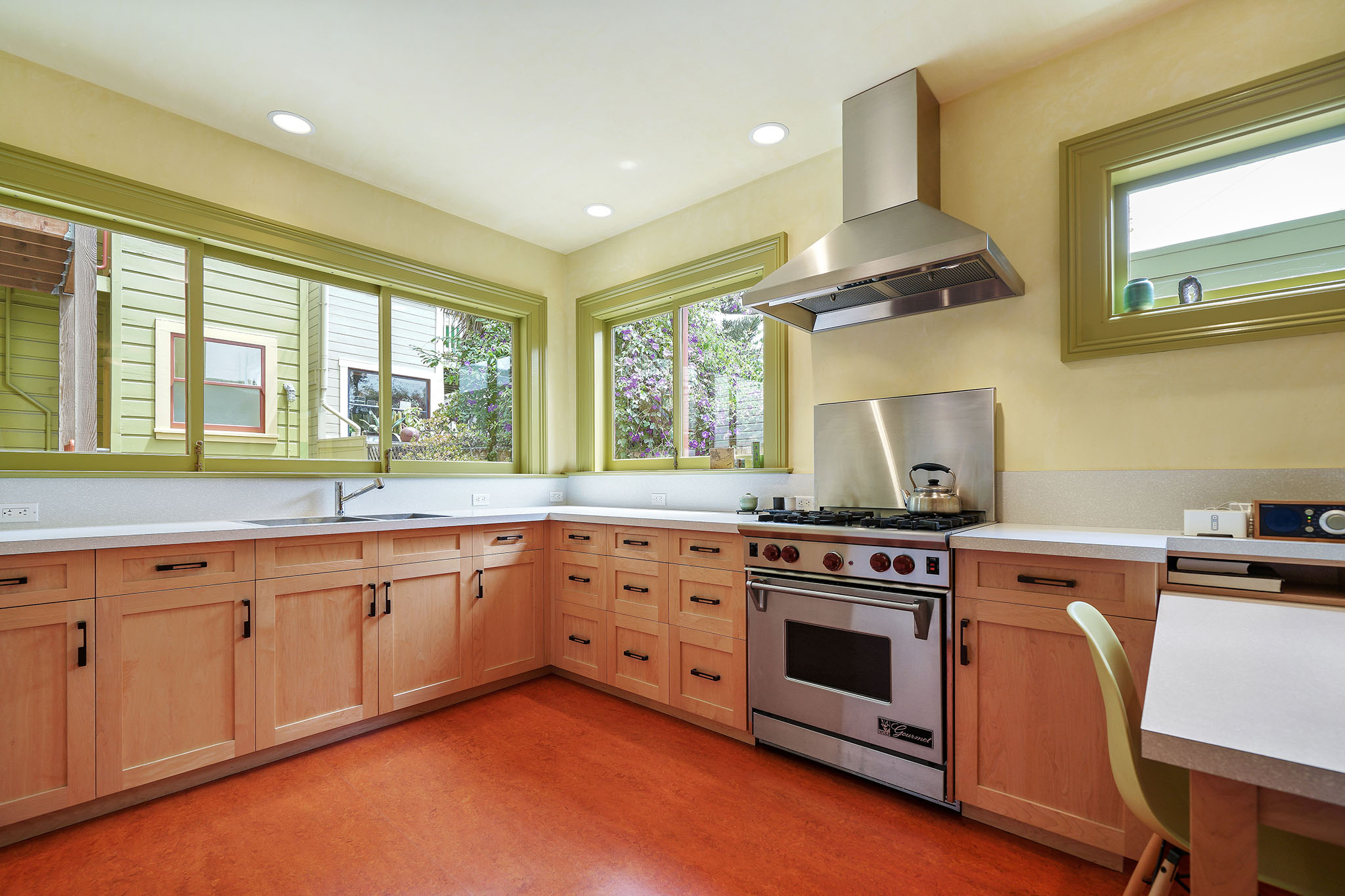 Close-up of the kitchen, showing windows, lots of cabinets and a large stove