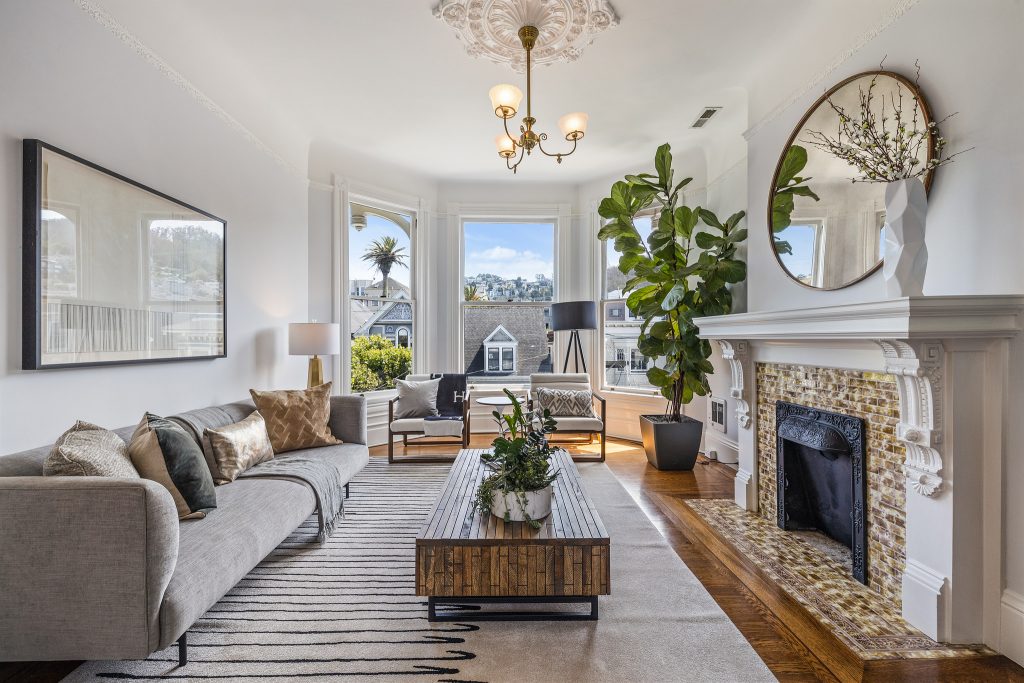 Living room showing a plant, wooden furniture and large windows