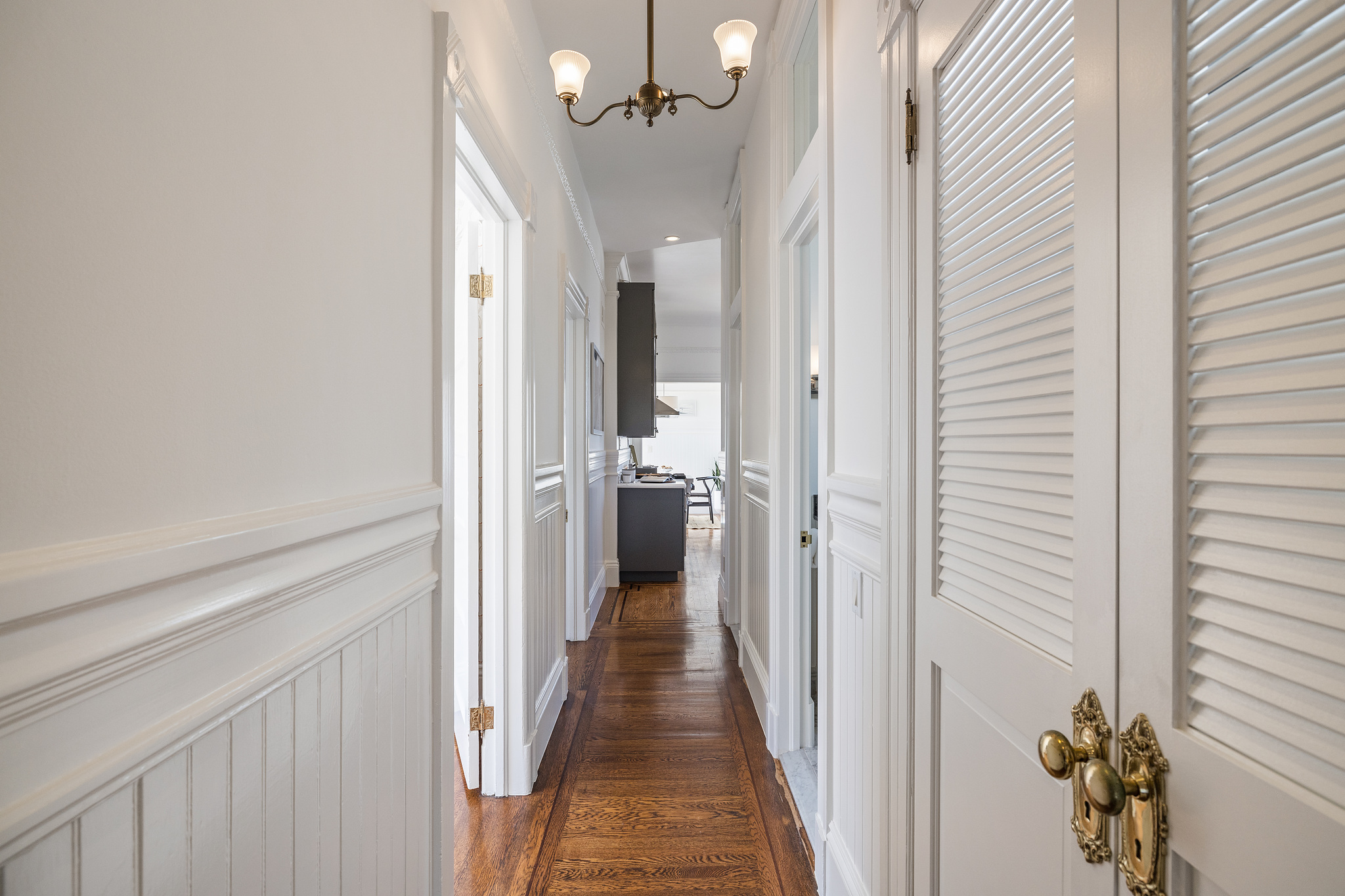 View of the hallway with a vintage fixture and wood floors