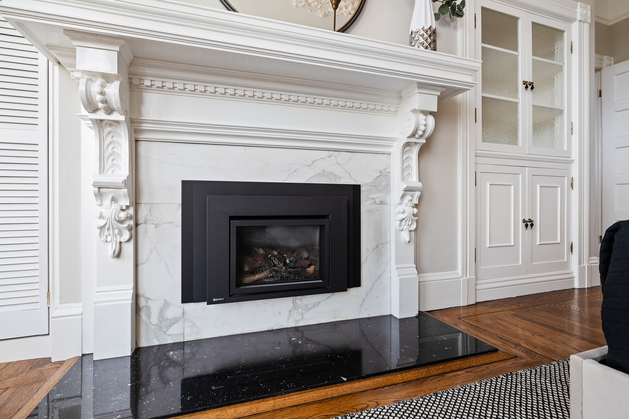 Close-up of the fireplace in the primary bedroom, featuring intricate woodwork
