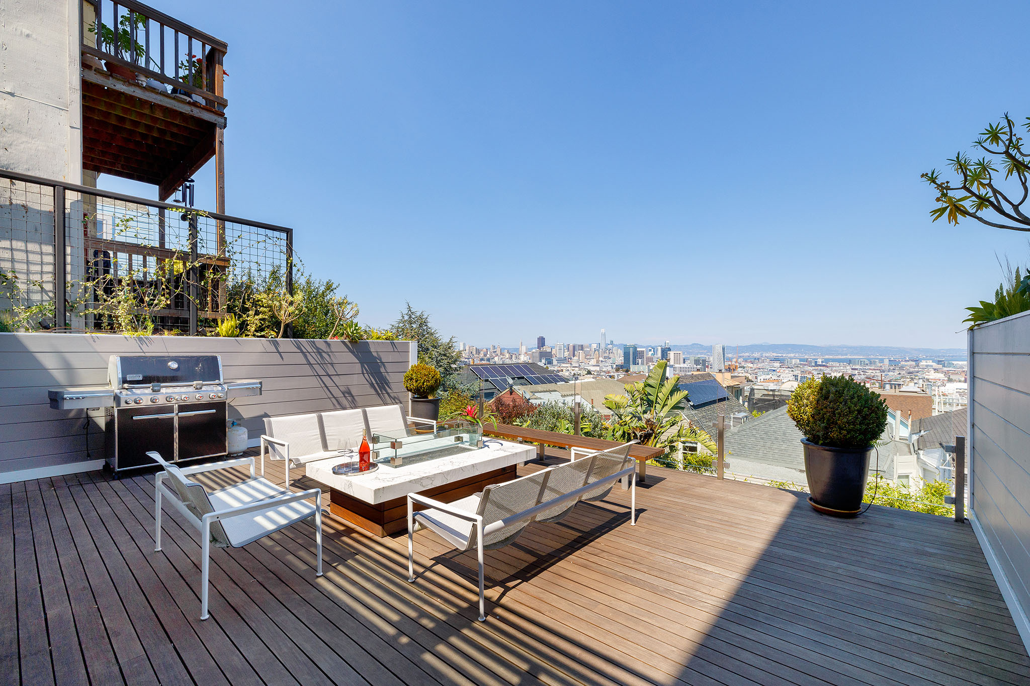 A white outdoor fireplace on a deck overlooking the San Francisco skyline