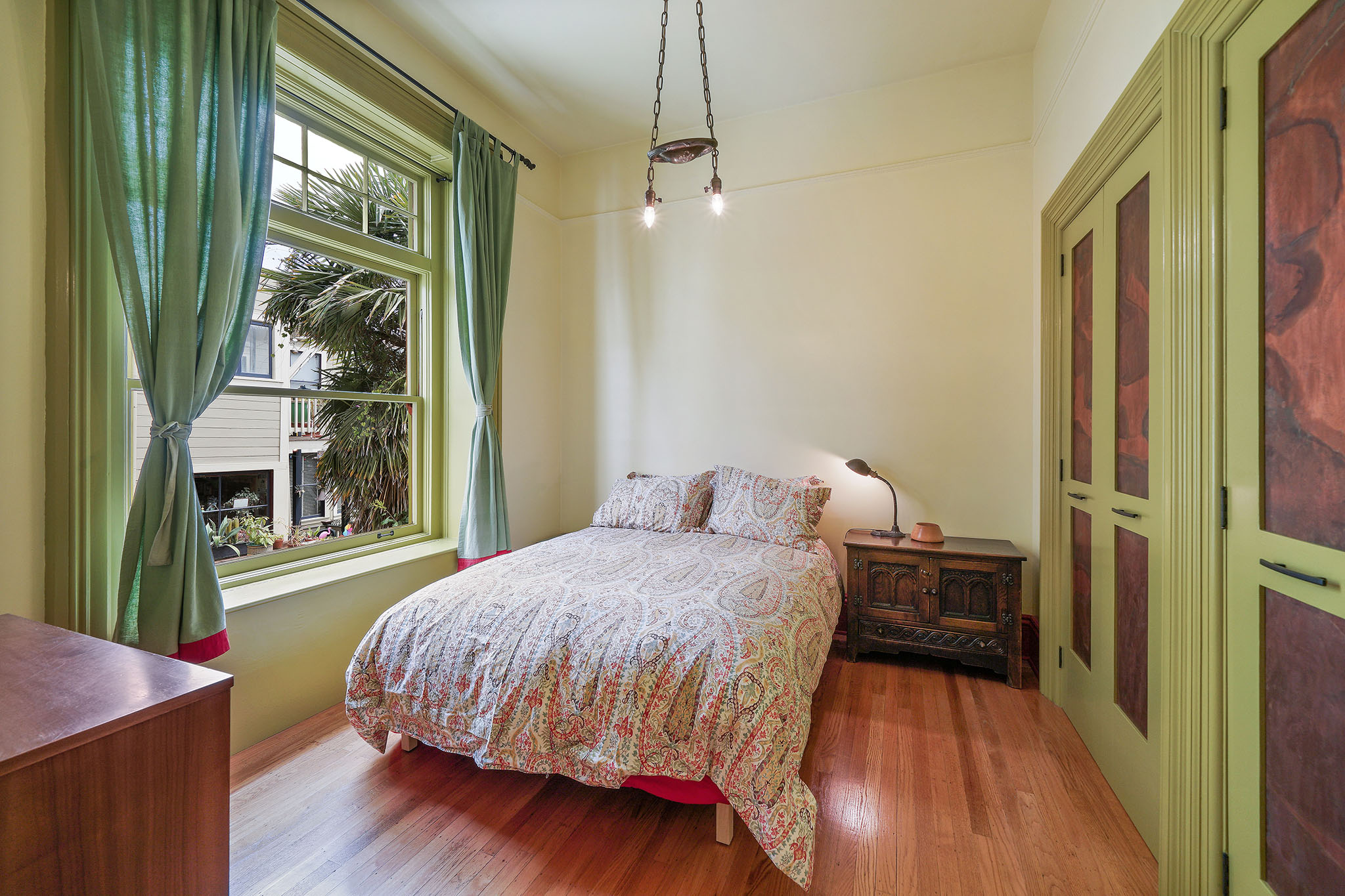 Bedroom with large windows, wood floors and a vintage light fixture