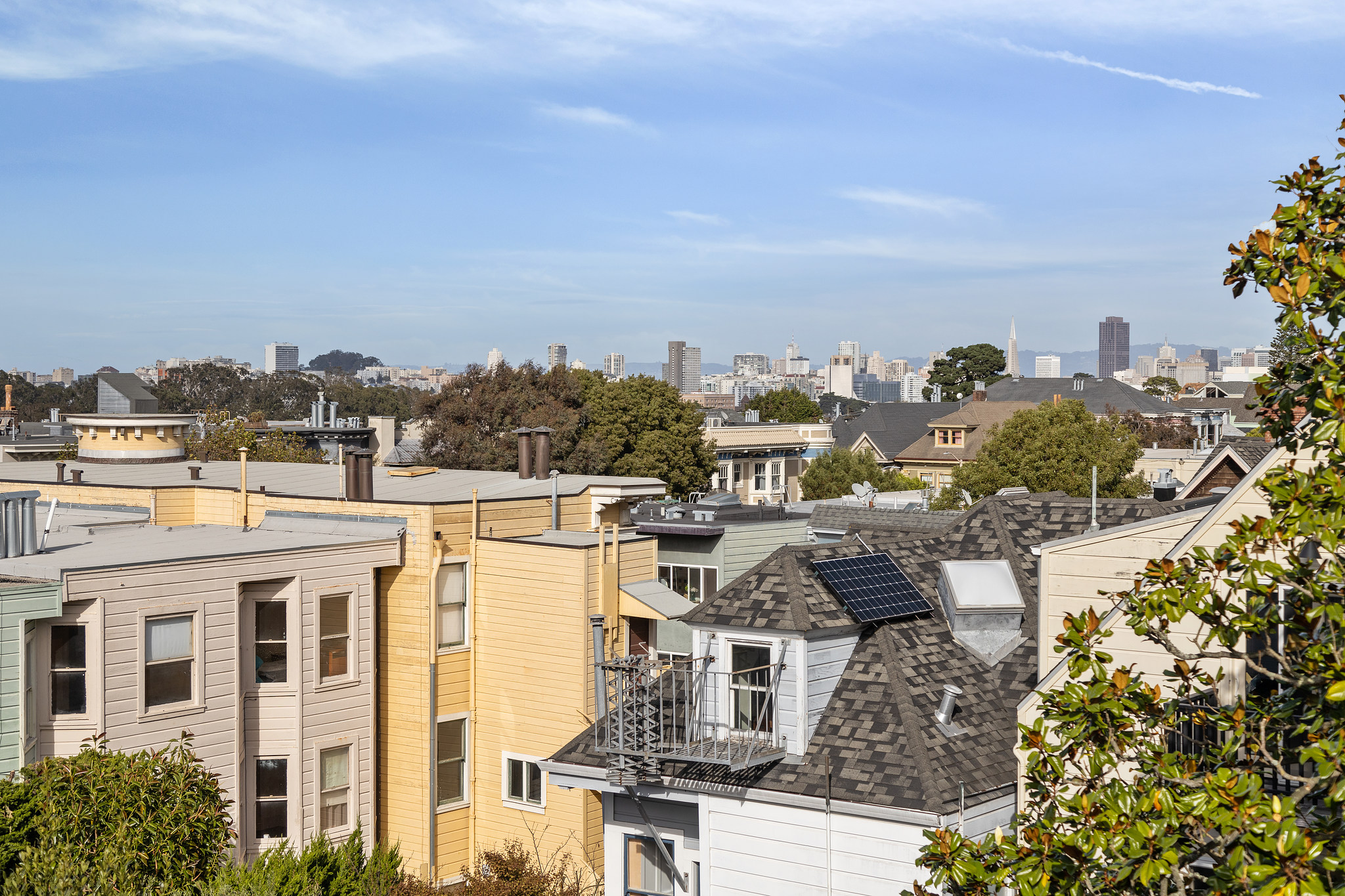 Cheery roof-tops and a blue sky is featured with a view of city