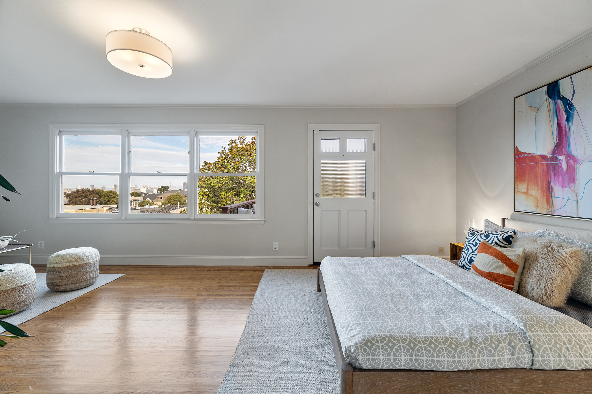 An expansive bedroom with three windows and a door leading to a private deck