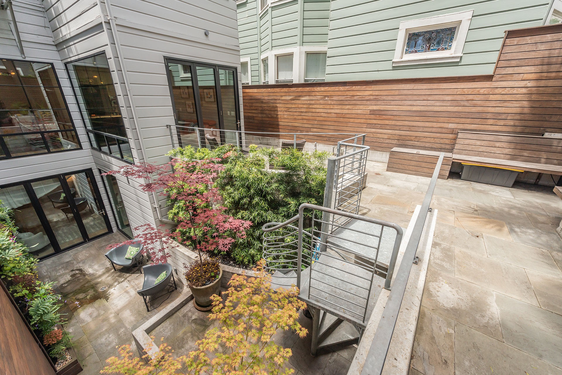 Looking over back yard from back corner.  There are planters and tile detail.  There are stairs that lead down to primary suite patio.