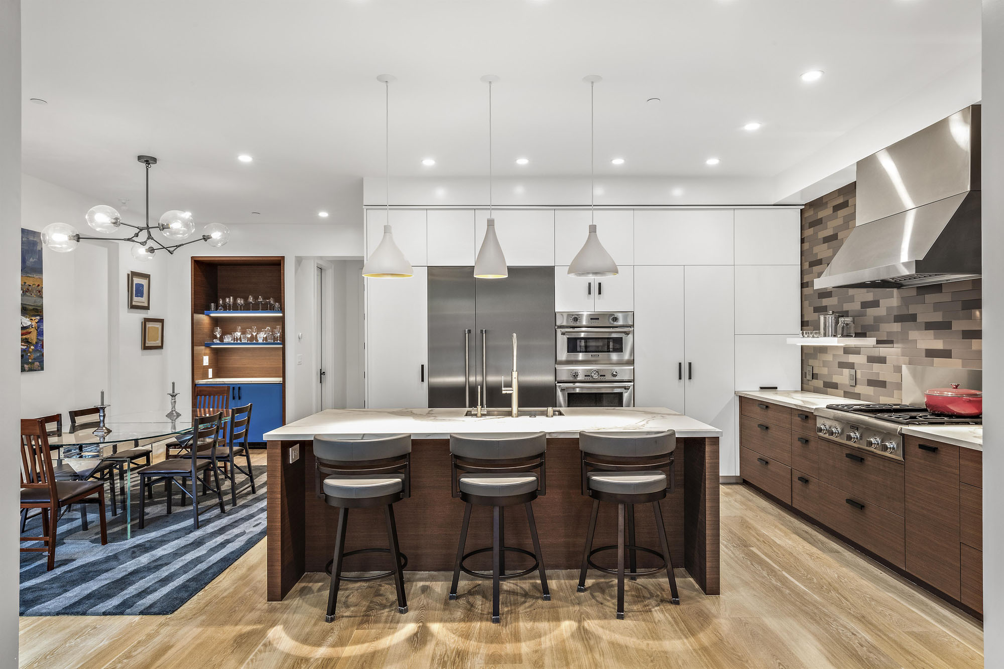 Looking at kitchen area from living room.  The island is center in this photo with the three stool and light pendants.