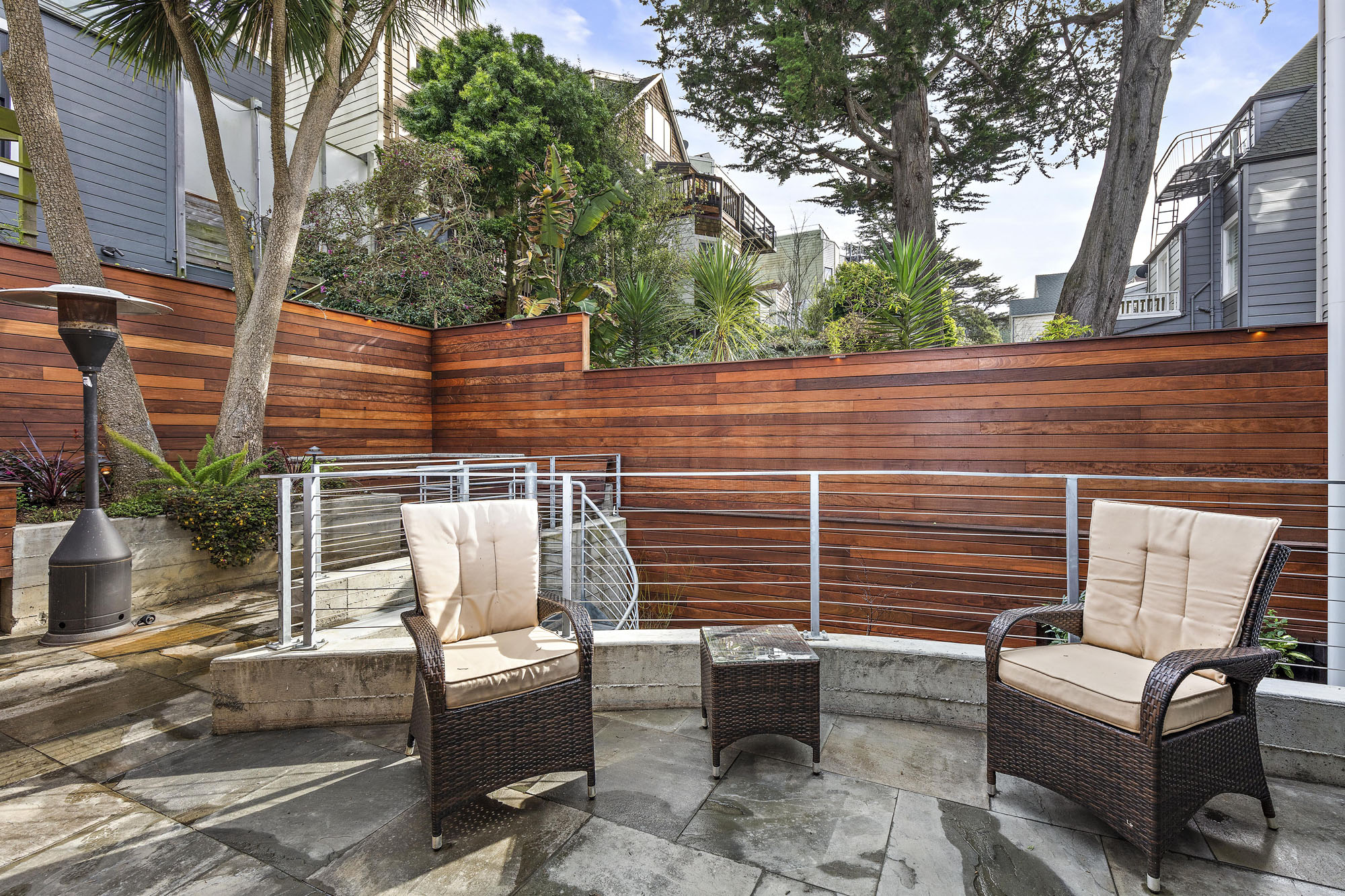 Sitting area in backyard that has two chairs and small table.