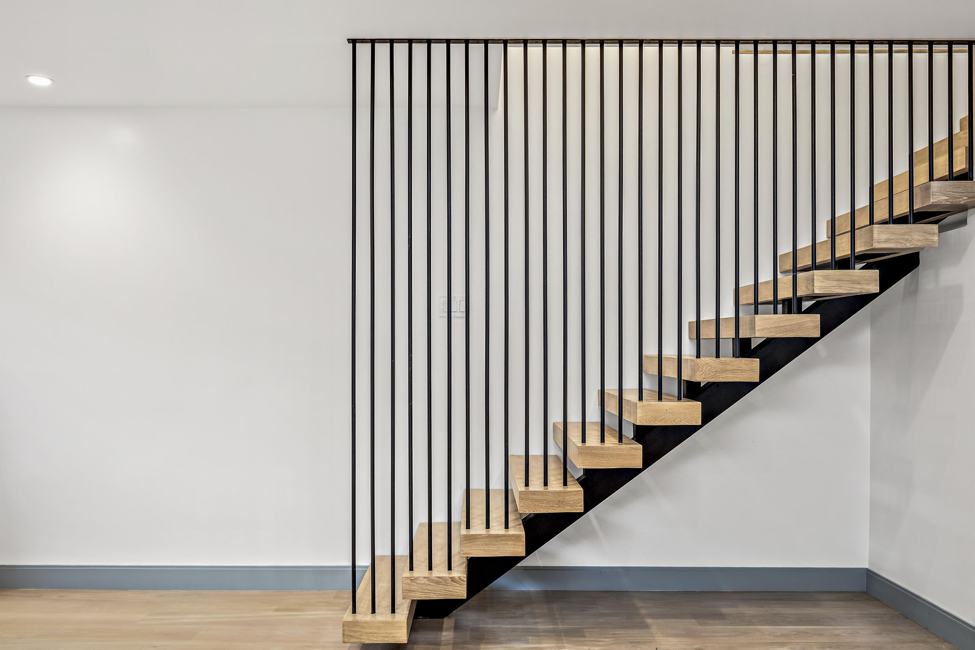 Staircase that leads to lower level. Stunning step to ceiling steel rod detail on side of steps.