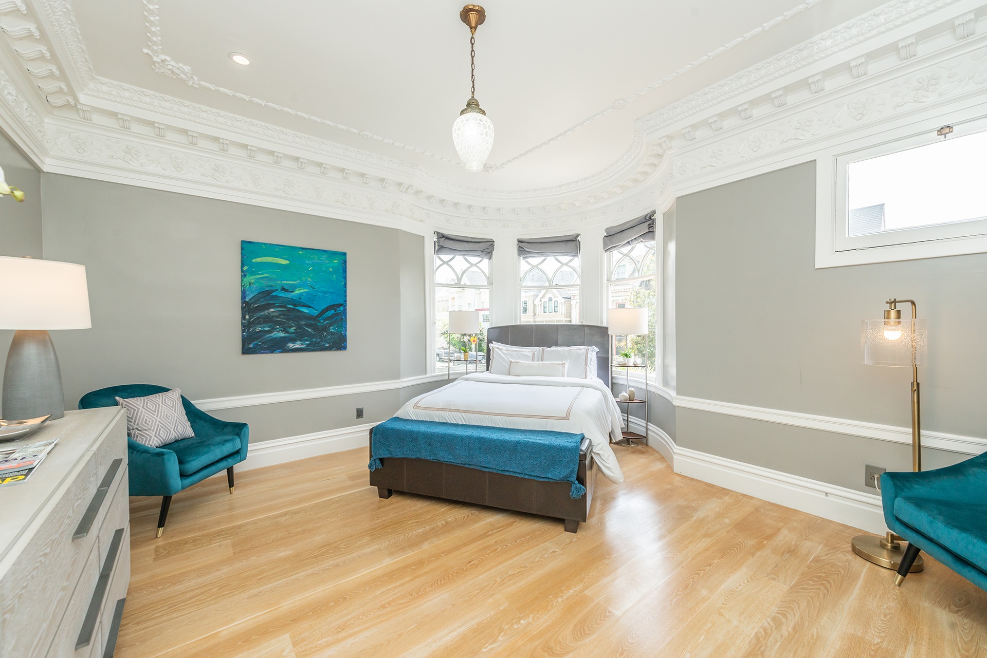 Primary bedroom that has bed centered under bay windows. There is stunning crown molding detail on the ceiling in this room.