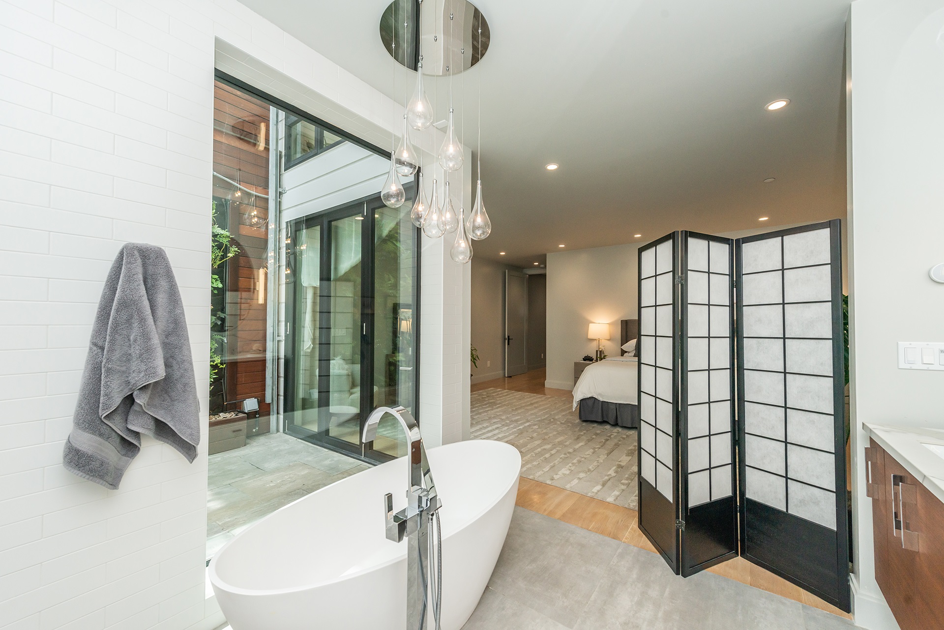 Bathroom has large floor to ceiling window that looks out at plant wall, and patio.