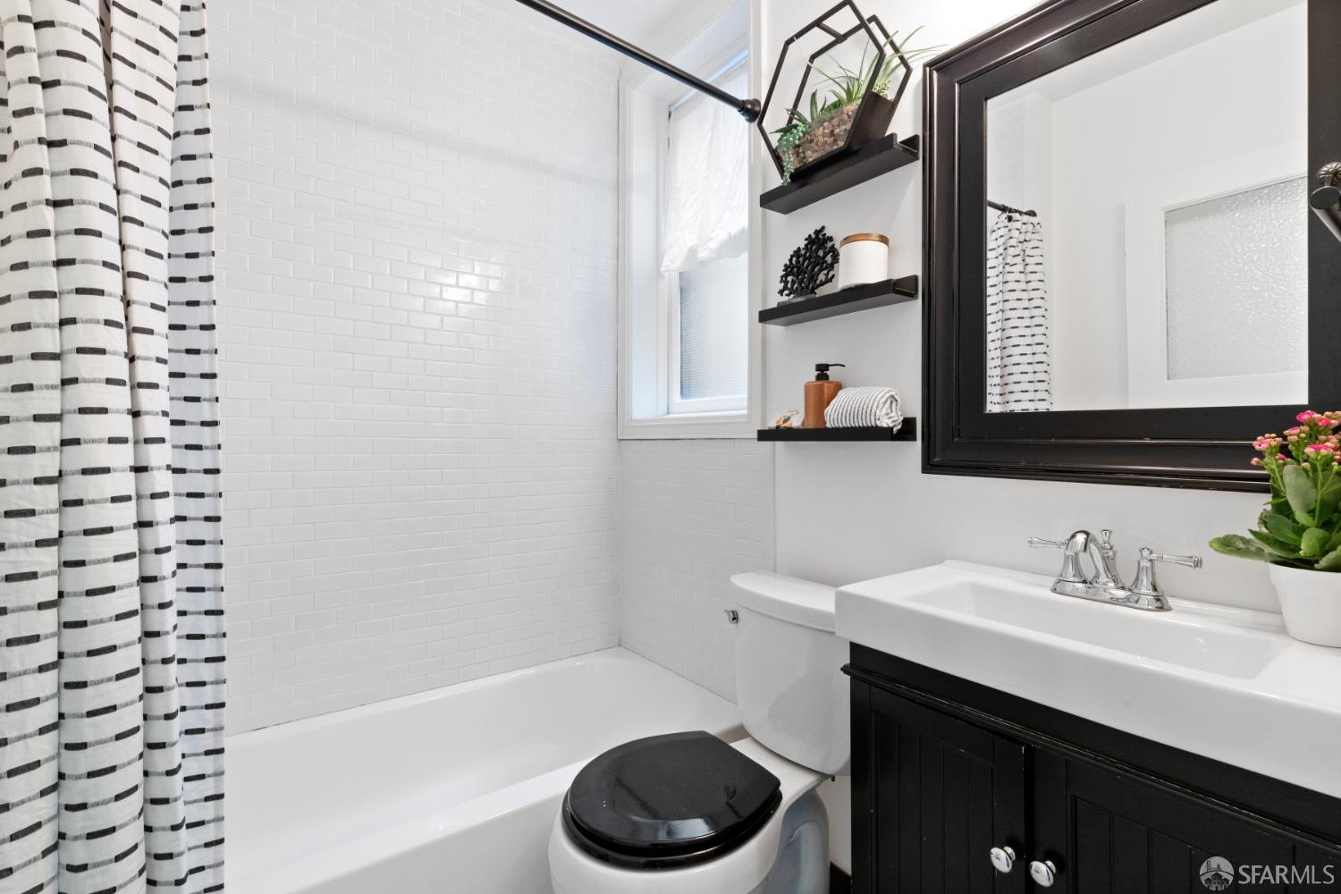 Bathroom has shower/bath combo with white tile.  The is a window also.
