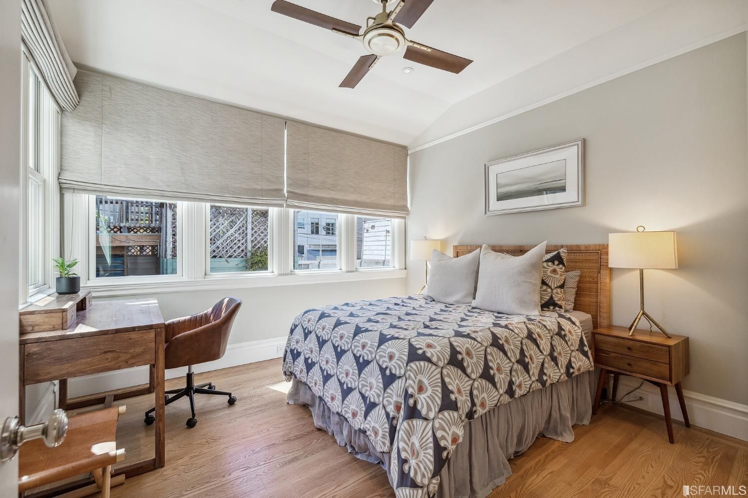 Bedroom one with wood floors and several large windows