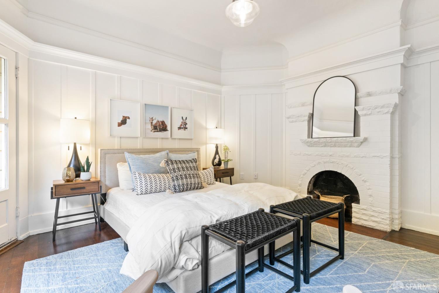 Bedroom in upper unit has lots of molding detail and brick fireplace that is painted white.