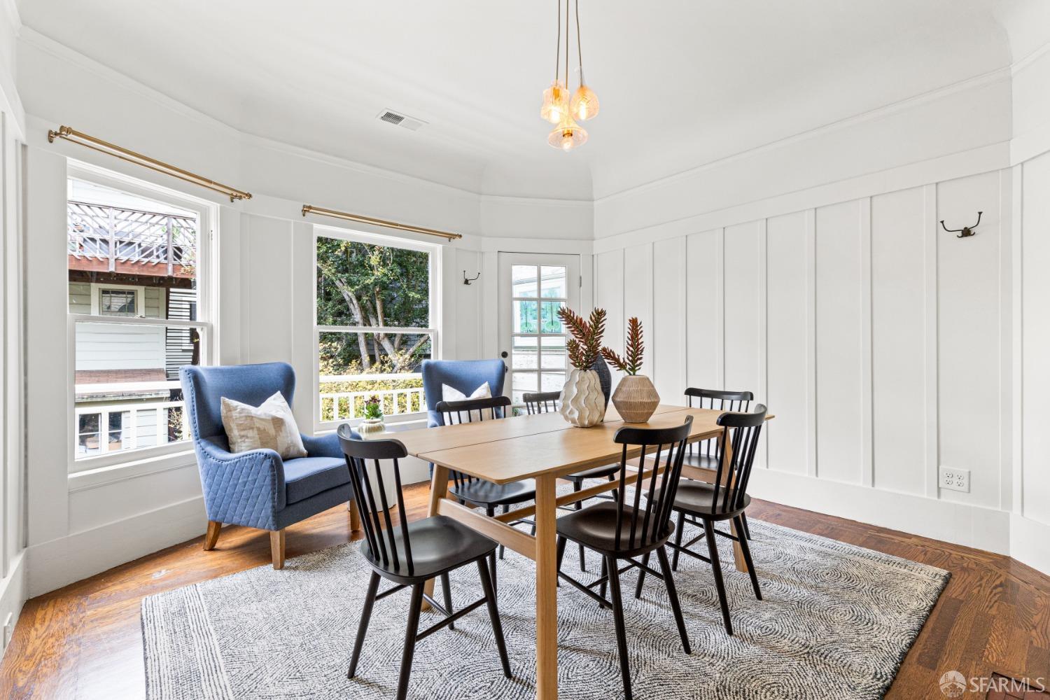Dining room has a table that seats 6 and has two plush chairs under windows.