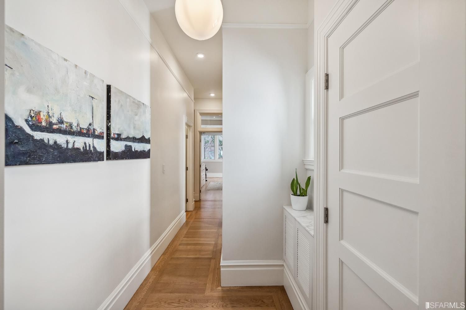 View of the hallway featuring wood floors, and a window nook ideal for plants