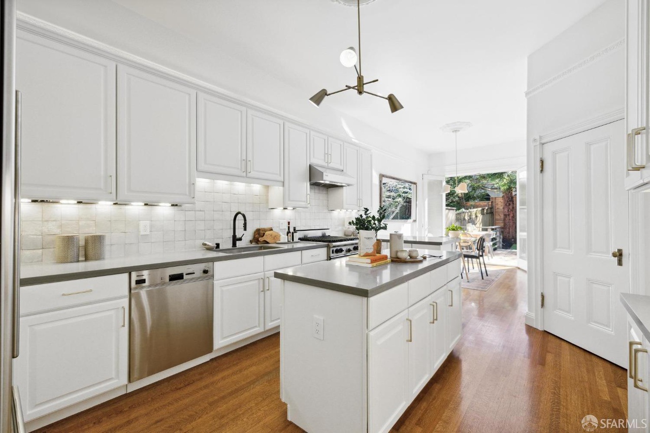 Kitchen has white tile backsplash and small island.