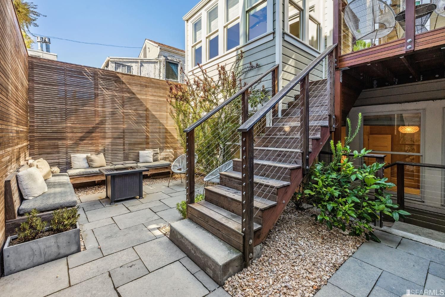 Lower patio with outdoor living space and steps leading to the upper deck