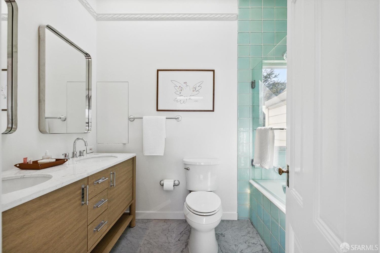 On suite bathroom has grey chevron grey tile floors and shower has teal green tile detail.