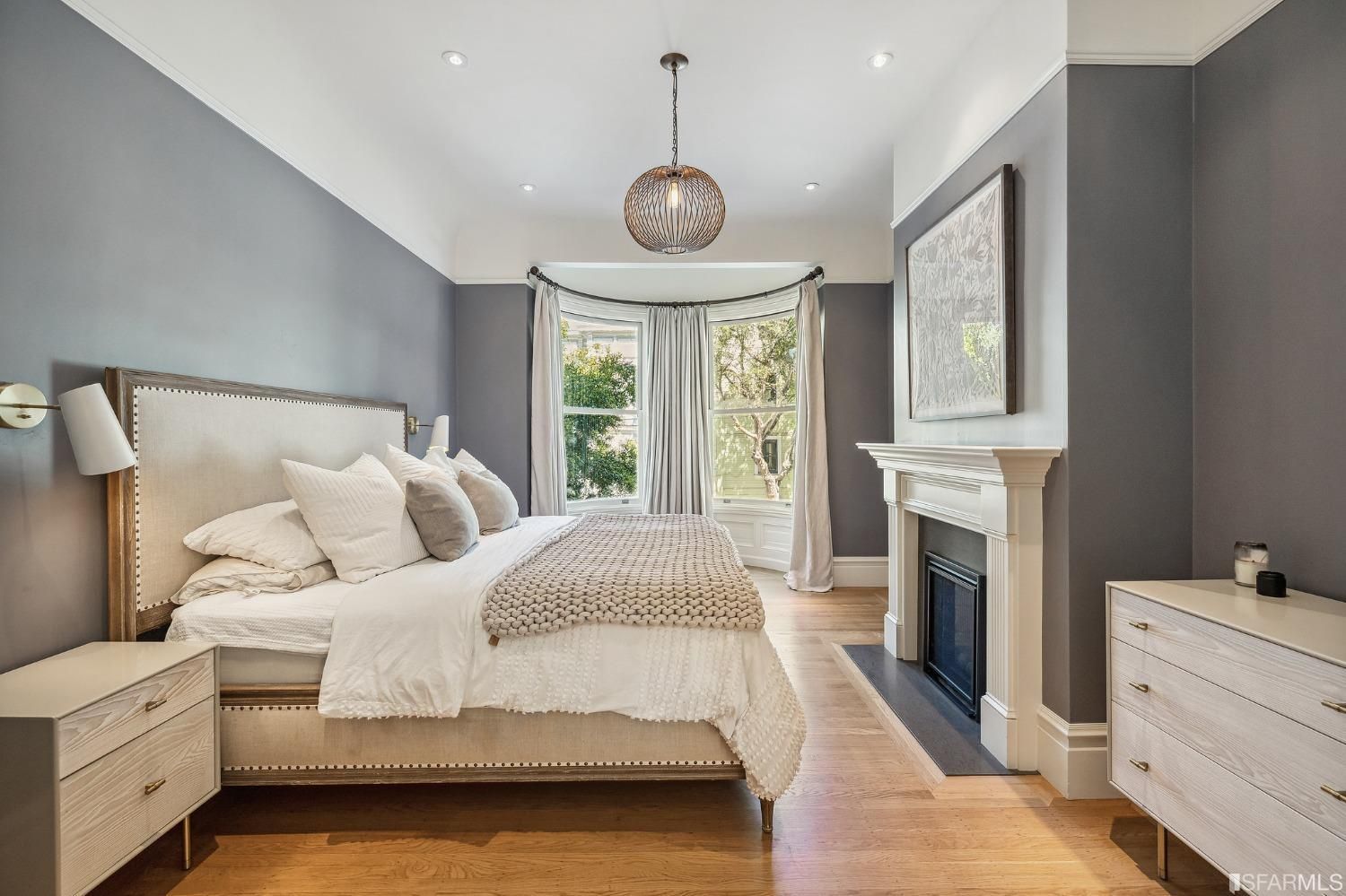 Primary bedroom, featuring a bay window and wood floors