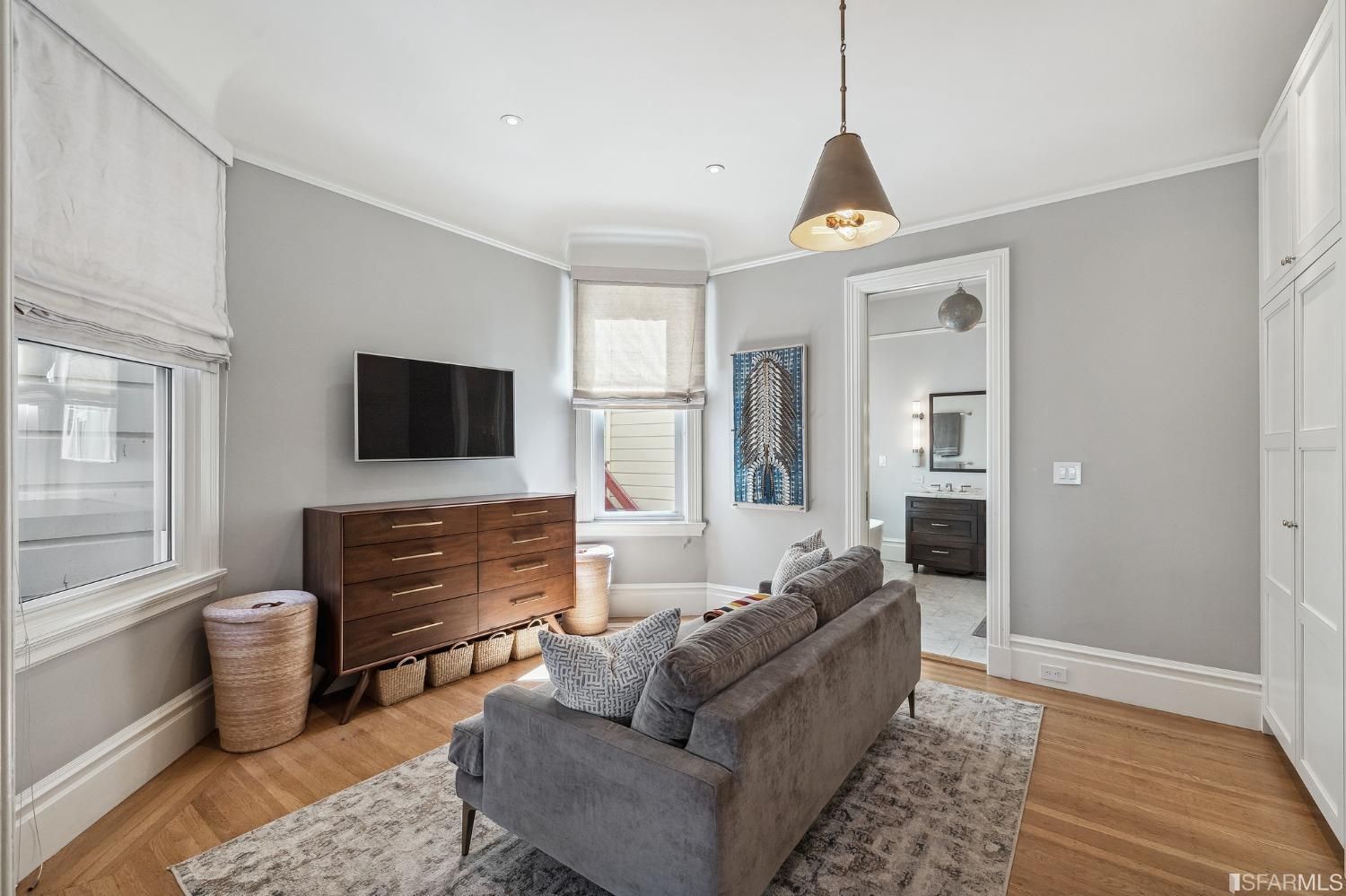 View of the sitting area adjacent to the primary bedroom suite, featuring two windows and wood floors