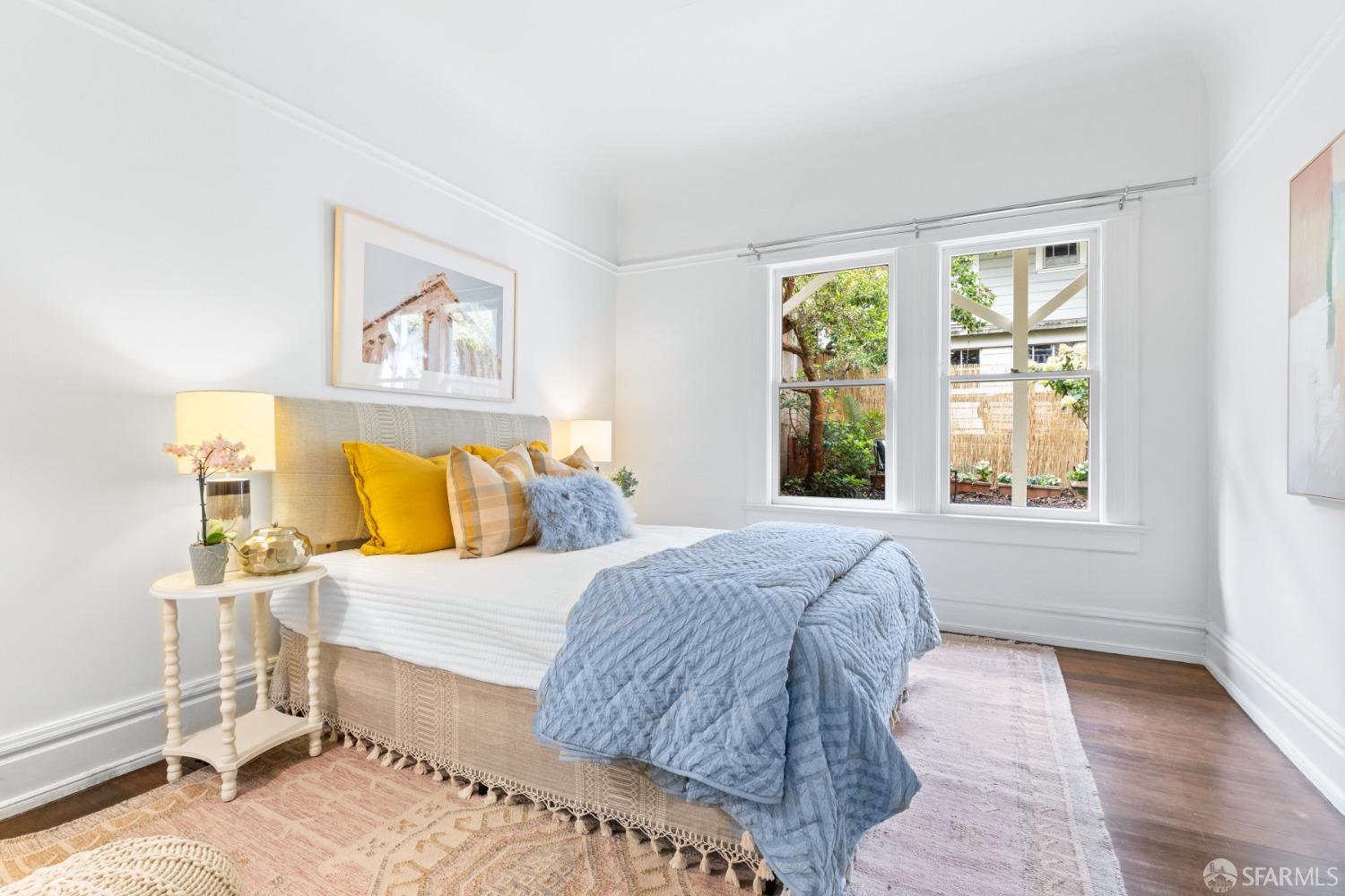 Bedroom has wood floors and windows that look out back